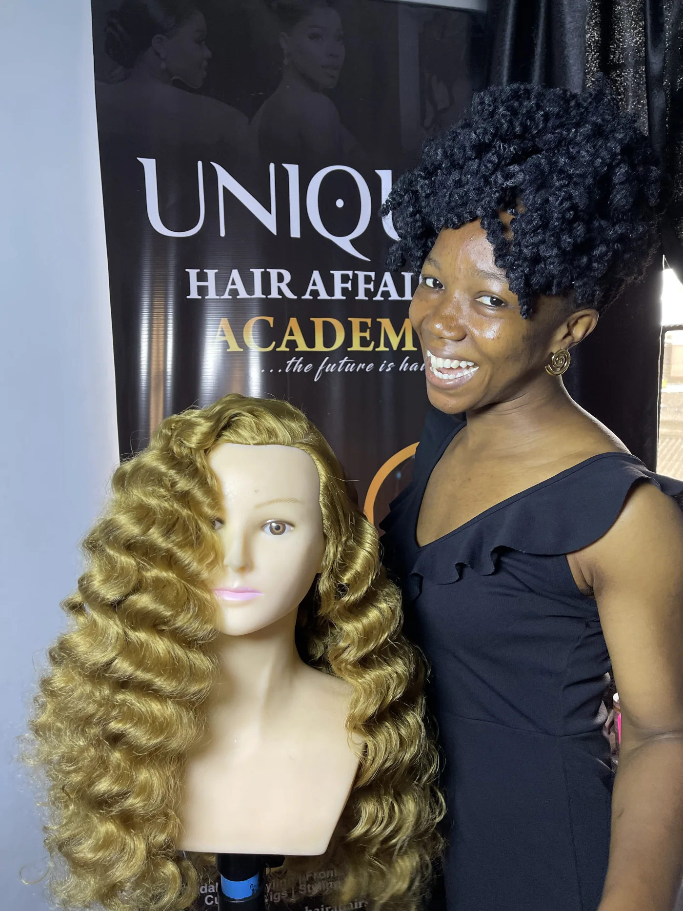 Academy portrait beside a mannequin styled in blonde waves at Unique Hair Affairs